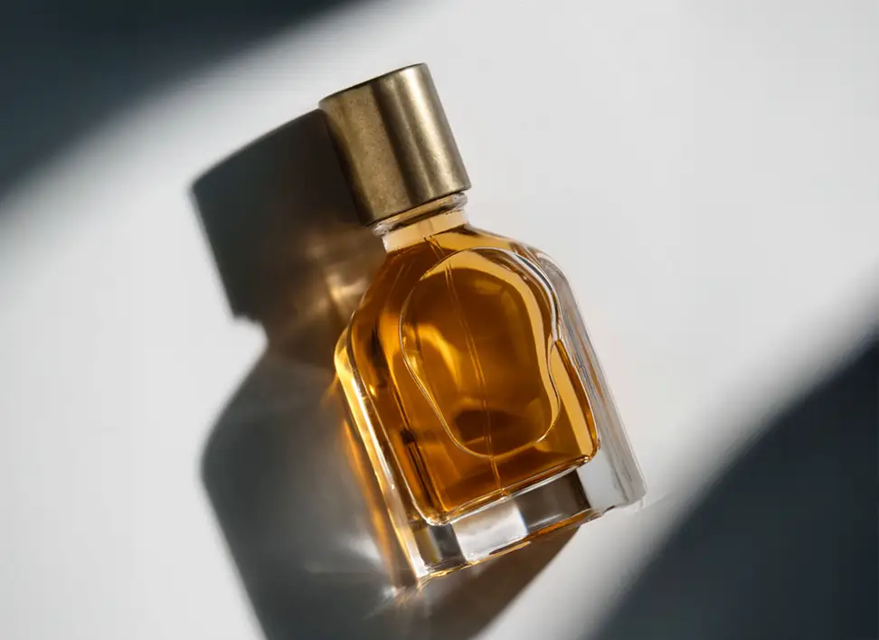 Minimalist glass perfume bottle filled with amber-toned fragrance on a clean background.